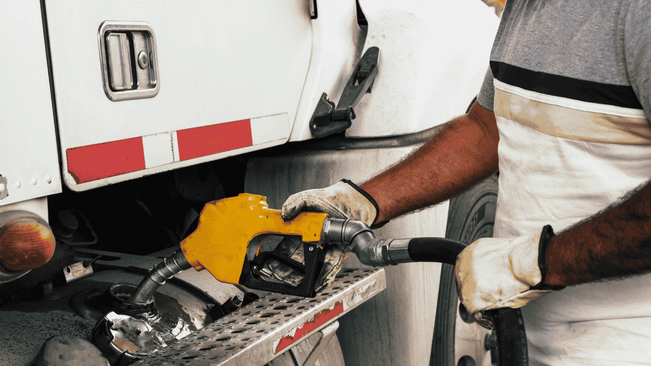 A man fueling a semi-truck with diesel at a gas pump.