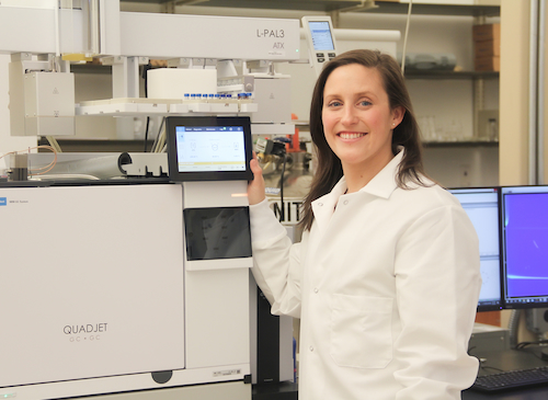 Dr. Kate Perrault-Uptmor posing with a LECO QuadJet GCxGC analyzer